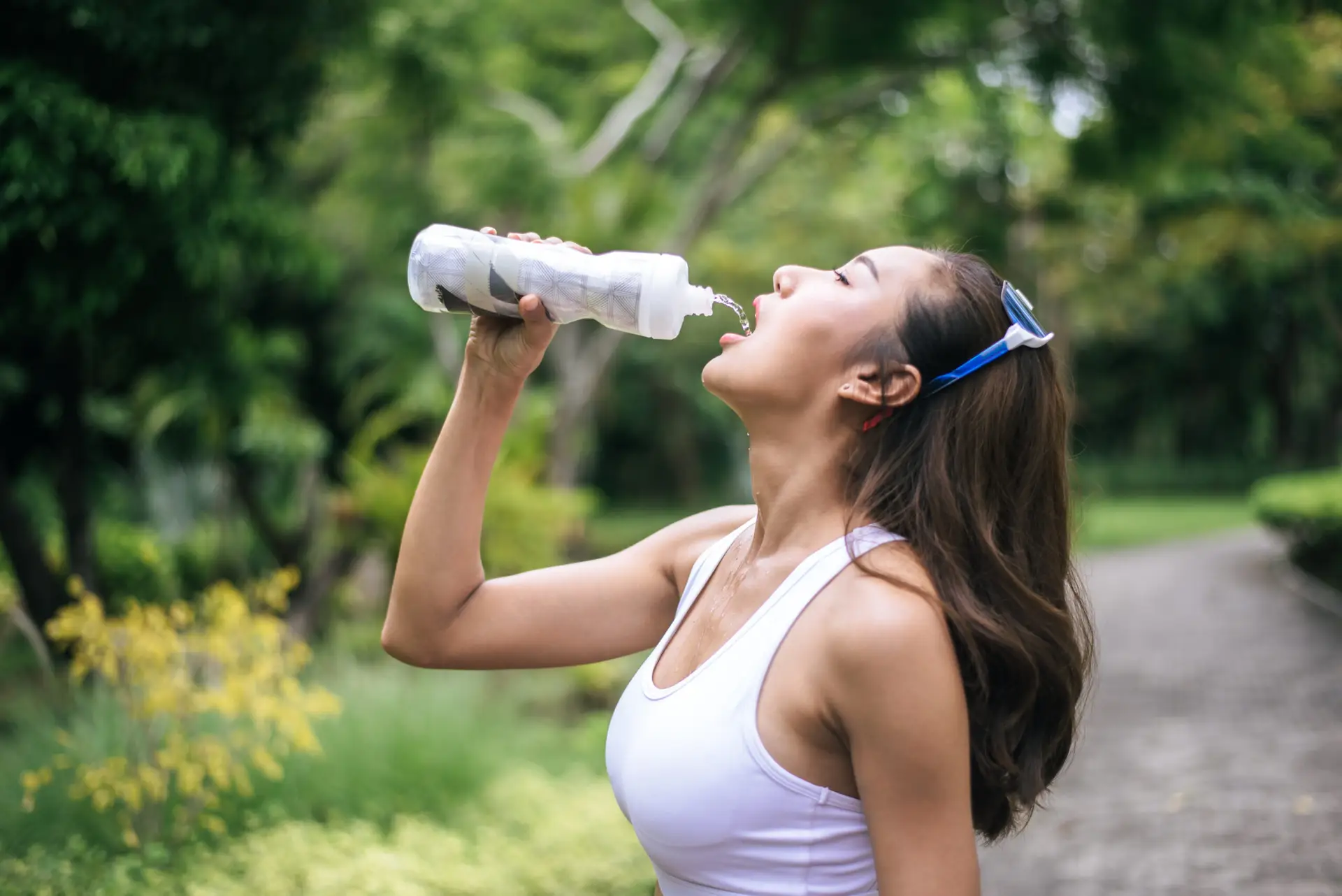 Young healthy woman drinking water from plastic bottles after jo